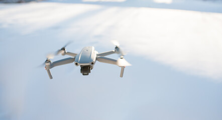 The drone is flying over the ground in the sky. take pictures from the sky in winter. the drone lands on the ground