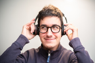 Happy young boy listening to music with his headphones on a clear background