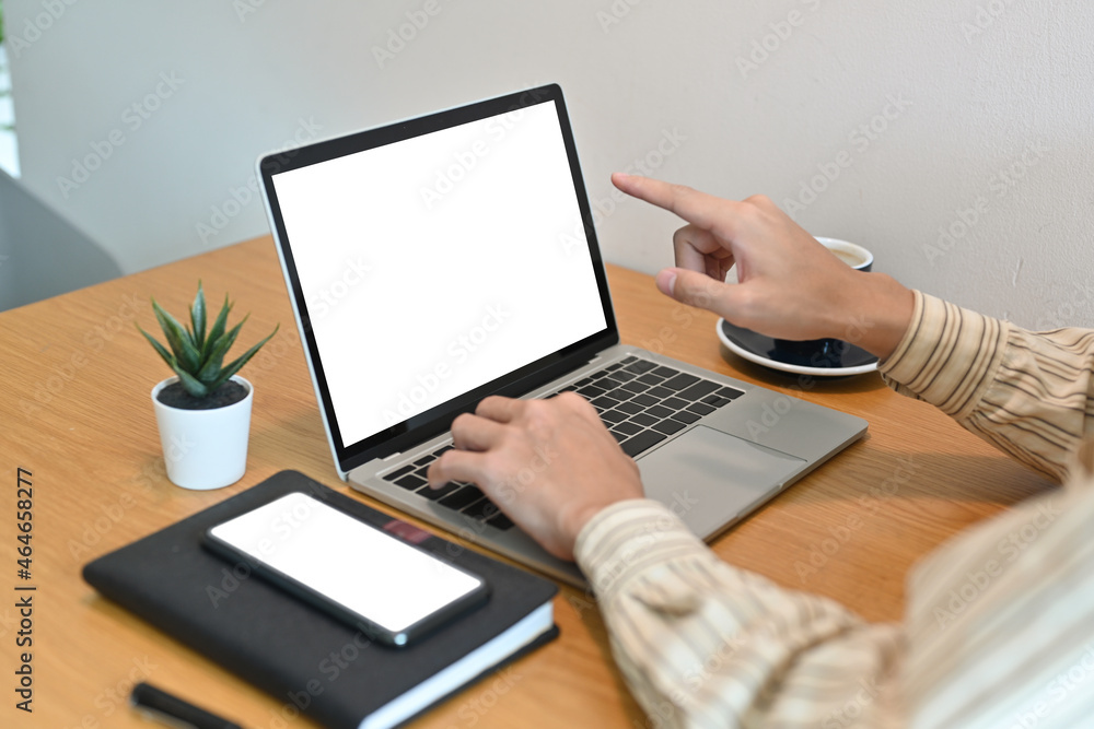 Poster cropped image of an office man typing on a computer laptop and pointing finger to the white blank sc