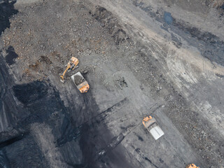 the excavator loads the earth into the truck, digs the earth, large machinery. a flying drone. top view