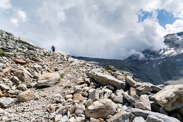 Ein Wanderer unterwegs Richtung Antronapass, Schweiz und Italien. Gebirgübergang in den walliser Alpen in der Nähe von Saas-Almagell, Stausee Mattmark, Schweiz. Ein Mann allein.