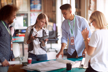 Fototapeta premium group of young people at work, looking at video shooting plan, analyzing drone.