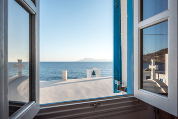 Blick durch ein offenes Fenster auf eine Kirche, das Meer und eine griechische Insel vor Lefkos, Karpathos, Griechenland. Vorlage, Textfreiraum, Werbung, Reisen.