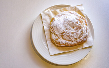 typical dessert of Menorca: ensaimada. on white plate and white table