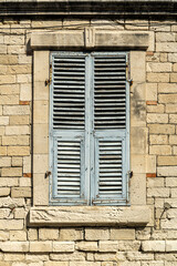 Fototapeta na wymiar Shuttered window in stone wall