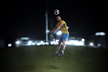 Fototapeta na wymiar A professional soccer player demonstrates complex moves in the soccer arena wearing a yellow jersey and blue shorts.