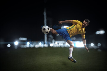 A professional soccer player demonstrates complex moves in the soccer arena wearing a yellow jersey and blue shorts.