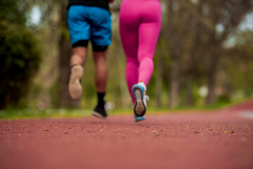 Cropped view of couple jogging together on running track in park