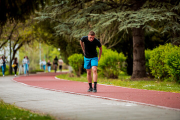 Young guy is jogging on running track in park