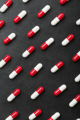 A pattern of red and white pill capsules on a black background background.