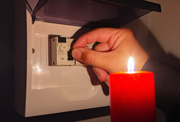A man's hand turns ON automatic fuses during a electric power outage at home. Blackout city,...