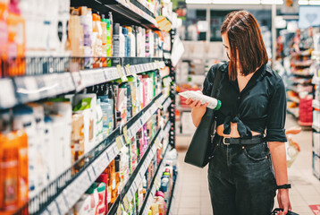 Young woman choosing care cosmetic in a supermarket. shopping