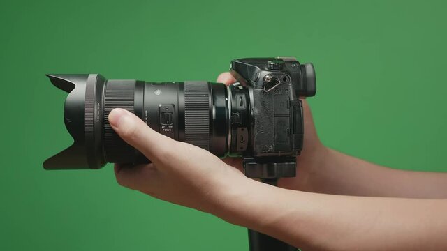Hand Adjusting Zoom And Focus On Digital Camera Lens On Green Screen Chroma Key. Photography Concept
