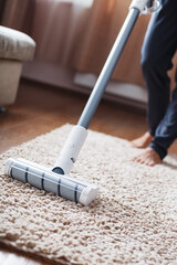 The turbo brush of a cordless vacuum cleaner cleans the carpet in the house in close-up