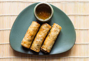 portion of fried Mon Nem, Vietnamese fried crispy spring rolls on green plate