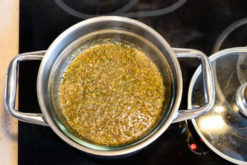 top view of medicinal herbs and plants in water bath on ceramic hob at home kitchen