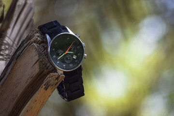 Naklejka premium Man hand watch on grass green plant, nature close up flora garden clock wallpaper background photo