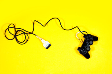black joystick, game controller with broken cable isolated on yellow background