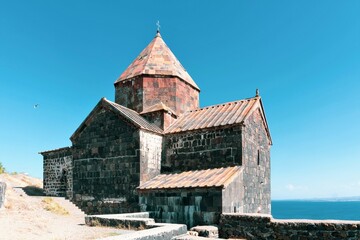 Armenia, Lake Sevan, September 2021. Medieval Christian temple in the shape of a cross on the top of a mountain.