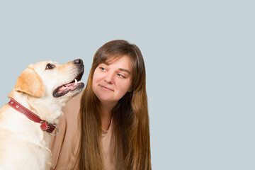 Portrait of a young beautiful girl with long hair and a labrador dog, on a blue  background. The image has a blank space for your text.