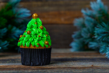 Christmas tree made of cupcake, cream decorated with gold balls. New Year card. Christmas in a rustic style. Copy space. Minimalism. Blurred background.