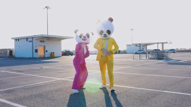 Happy people wearing a panda giant head dancing and having fun in a parking lot