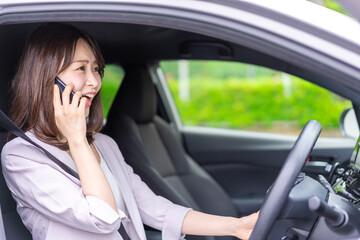 スマホを使いながら車を運転する女性