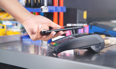 Customer paying for purchases contactless with smartphone.