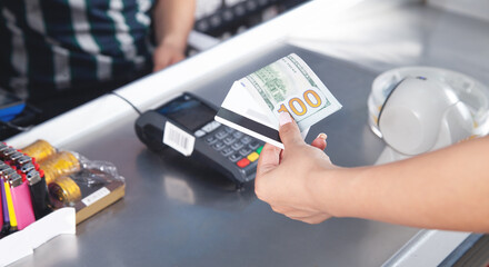 Woman paying with credit card dollar in supermarket.