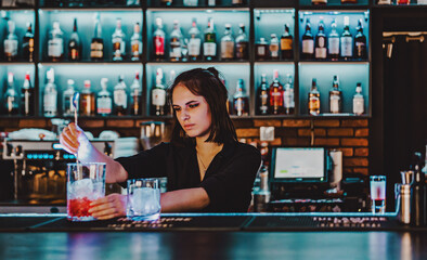 Portrait of young attractive woman bartender Making Cocktail in bar