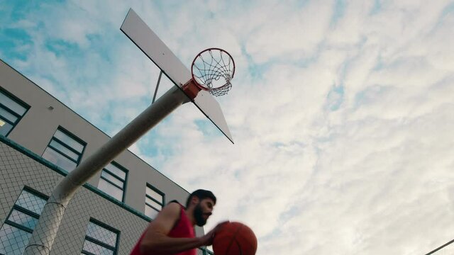 In a modern stadium tall guy very charismatic in a red sport suit playing basketball and throw the basketball in the basket