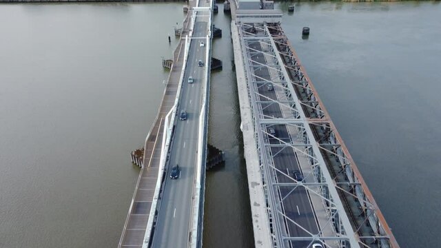 Temse bridge over the river Scheldt seen from above with traffic and cars driving on both side of the road near green trees in summer. Drone aerial bird eye view revealing Temse town