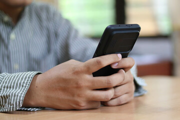 Person using a social media marketing concept on mobile phone with notification icons of like, message, comment and star above smartphone screen.