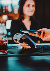 Contactless mobile payment. Payment terminal and smartphone in hands in bar
