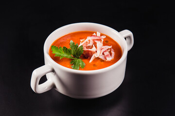 Tomato soup with bacon in white mask on a black background