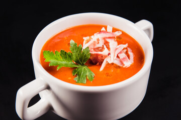 Tomato soup with bacon in white mask on a black background