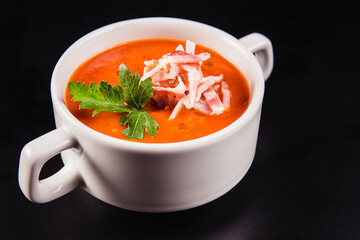 Tomato soup with bacon in white mask on a black background
