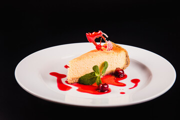 Berry cake with decoration on a round white plate on a black background