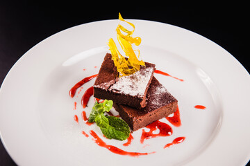 Layered coffee cake with decoration on a round white plate on a black background