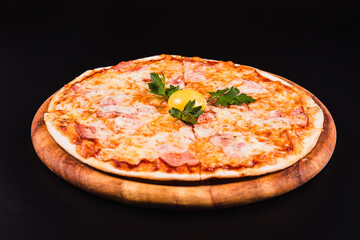 Round pizza with an egg on a wooden board on a black background
