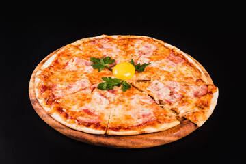 Round pizza with an egg on a wooden board on a black background