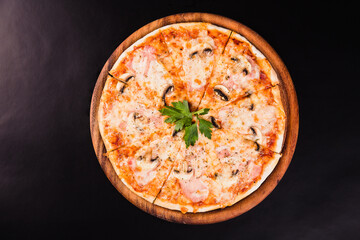 Italian pizza with mushrooms on a wooden board on a black background