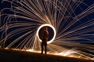 Iron wool circle drawing light fireworks. Burning Steel Wool spinning, Trajectories of burning sparks at night. Movement light effect, steel wool fire hoop. long exposure light painting, Pyrotechnic