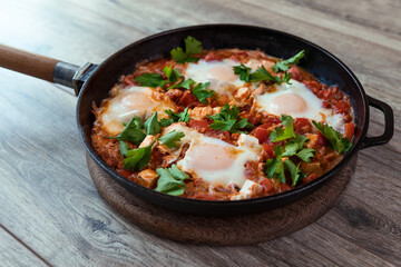 Shakshuka in a frying pan, poached eggs in spicy tomato sauce. Summer breakfast with eggs and tomato sauce.