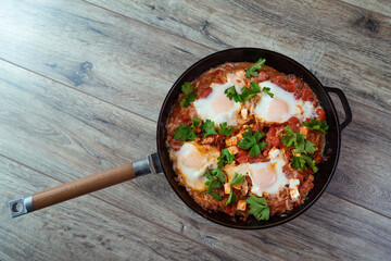 Shakshuka in a frying pan, poached eggs in spicy tomato sauce. Summer breakfast with eggs and tomato sauce.