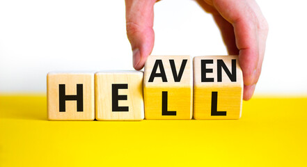 Hell or heaven symbol. Businessman turns wooden cubes and changes the word 'hell' to 'heaven'....