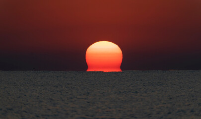 Spectacular sunrise. The sun rises from the sea. Optical illusion.