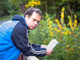 Man reading letter and leaning on the railing, worried and sad