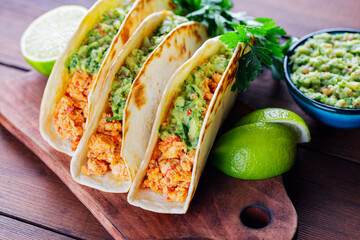 Tacos with fried minced meat and guacamole sauce on a wooden boards. Mexican tacos, cilantro and...