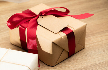 Christmas brown gift boxes and red ribbon with tag paper lay on the table, front view with copy space.